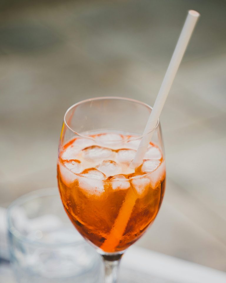 Close-up of a refreshing orange cocktail with ice in a wine glass.